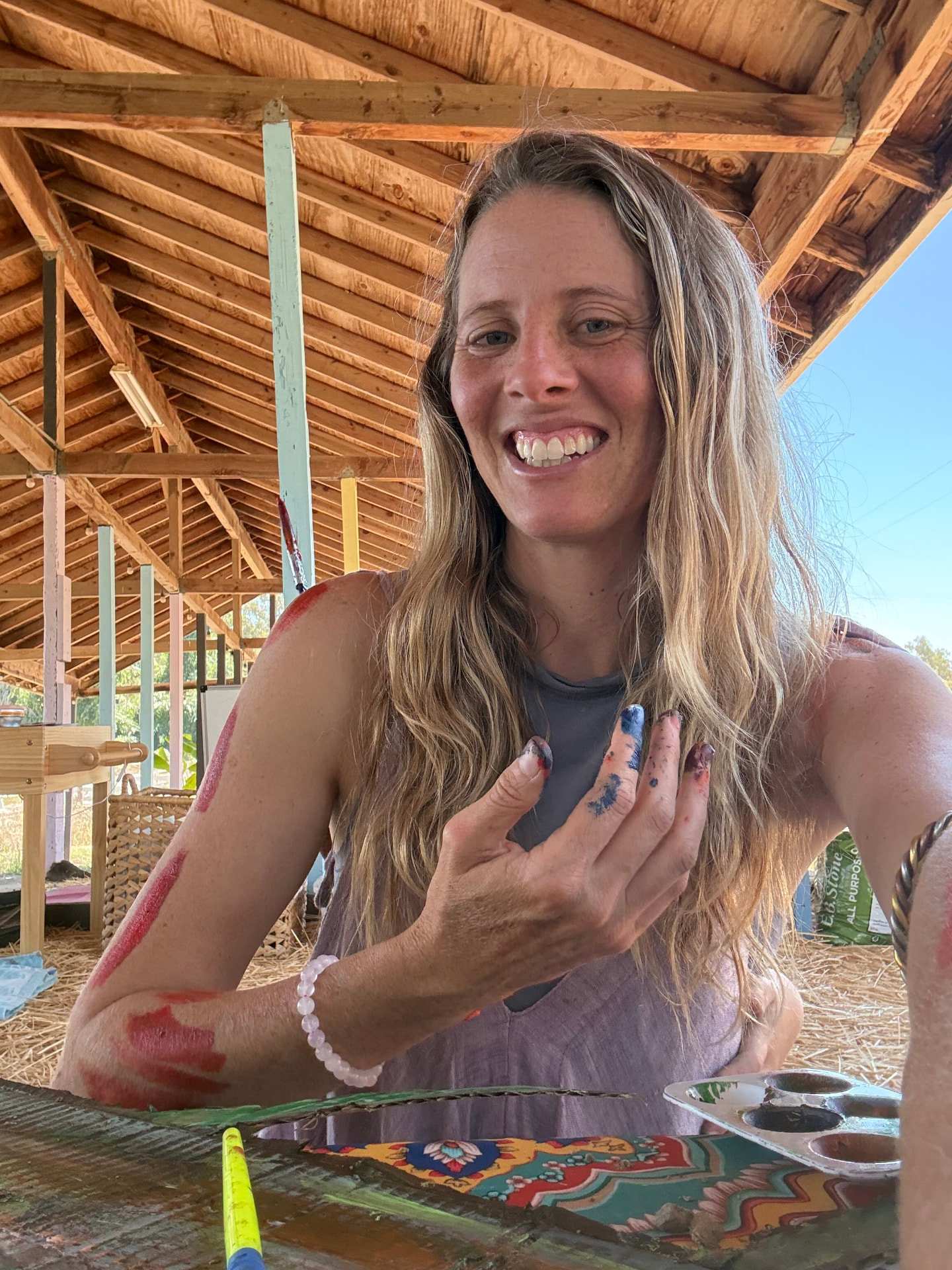 A guide holding up a paint-marked hand beside the barn art table
